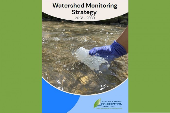 An image of a hand, in glove, collecting water sample, on cover of Watershed Monitoring Strategy 2026-2030.